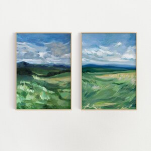 May include: Two framed landscape paintings with a green field and blue sky with white clouds. The paintings are in a minimalist style with soft brushstrokes.
