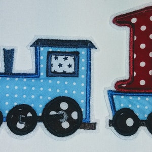 May include: A blue and white train with a red and white number one on the back. The train has a black chimney and wheels. The number one is on a blue and white carriage.