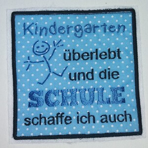 Könnte beinhalten: Blau-weißer gestickter Aufnäher mit weißen Punkten. Der Aufnäher sagt "Kindergarten überlebt und die Schule schaffe ich auch".