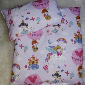 Op de afbeelding: Een roze en witte kinderbeddengoedset met een eenhoorn-, regenboog- en luchtballonmotief. De beddengoedset heeft verschillende kleurrijke illustraties, waaronder een eenhoorn, een regenboog, luchtballonnen en een kasteel.