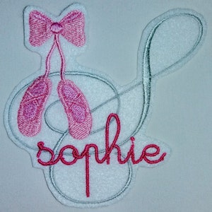Op de afbeelding: Geborduurde patch met een roze balletpantoffel en strik, een solsleutel en de naam "Sophie" in roze draad.