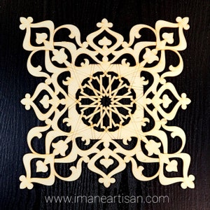 May include: A laser cut wooden design with intricate geometric patterns, resembling a snowflake or star. The design is symmetrical and features a central motif with radiating lines. The wood is light brown and the design is cut out against a black background. The website address "www.imaneartisan.com" is visible at the bottom of the image.