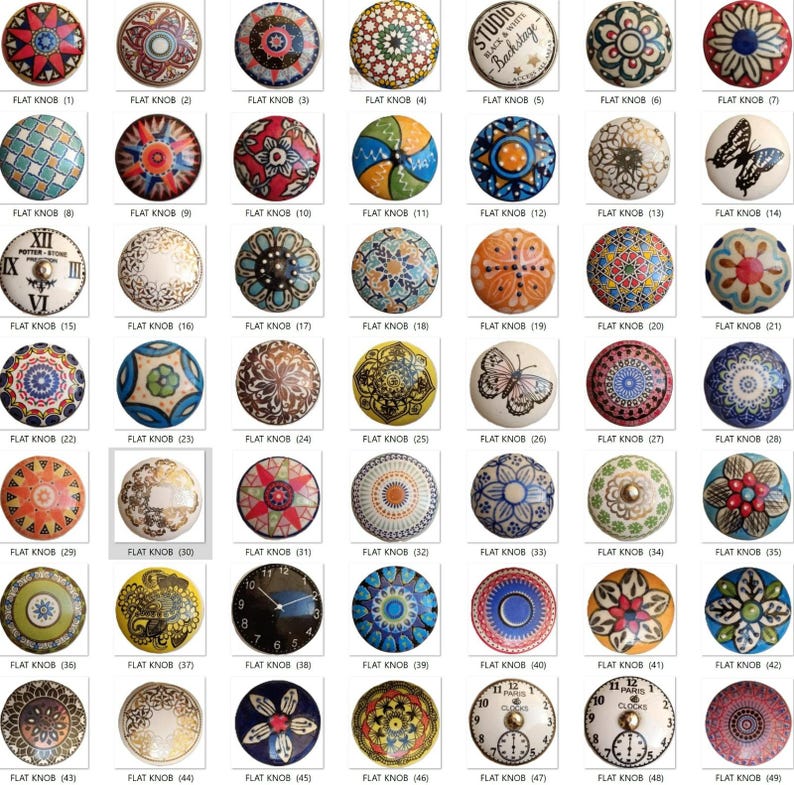 May include: A collection of flat knobs with various decorative designs. The knobs feature floral, geometric, and butterfly patterns in a range of colors, including blue, red, orange, and white. Some knobs have clock faces or text like "STUDIO".
