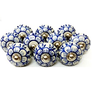 Peut inclure: Un ensemble de dix boutons de meuble en c&eacute;ramique. Chaque bouton pr&eacute;sente une base blanche avec un motif floral bleu et un centre en m&eacute;tal argent&eacute;. Les boutons sont dispos&eacute;s de pr&egrave;s sur un fond blanc.