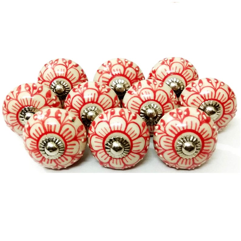 Peut inclure: Ensemble de boutons de placard en c&eacute;ramique cr&egrave;me avec un motif floral rouge. Chaque bouton est dot&eacute; d'une base m&eacute;tallique argent&eacute;e. Les boutons sont dispos&eacute;s de pr&egrave;s, mettant en valeur leur motif d&eacute;coratif.