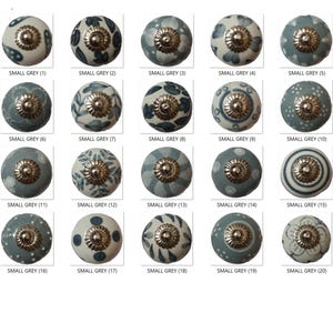 May include: A collection of twenty small, round cabinet knobs in various designs. The knobs are primarily gray and white with floral and geometric patterns. Each knob has a metallic silver base and is labeled "SMALL GREY" with a number.