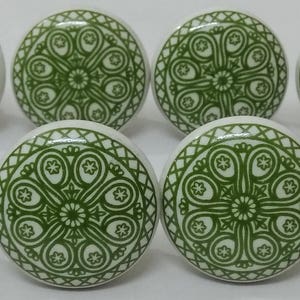 May include: Twelve green and white ceramic cabinet knobs with a decorative floral pattern.