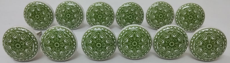 May include: Twelve green and white ceramic cabinet knobs with a decorative floral pattern.