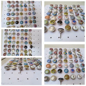 May include: A collection of decorative ceramic knobs with various colorful patterns, including floral, geometric, and abstract designs. The knobs are round with metal screws, suitable for furniture or cabinet hardware. The knobs are arranged on a white surface.