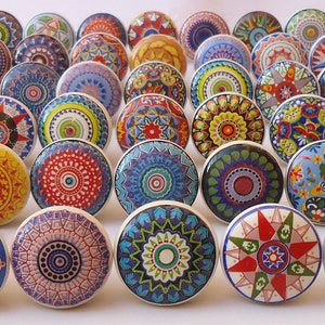 May include: Assortment of colourful ceramic drawer knobs with intricate patterns. The knobs feature a variety of colours, including blue, green, red, yellow, and white. Each knob has a unique design, with some featuring geometric shapes, floral motifs, and abstract patterns.