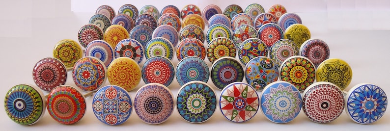 May include: Assortment of colourful ceramic drawer knobs with intricate patterns. The knobs feature a variety of colours, including blue, green, red, yellow, and white. Each knob has a unique design, with some featuring geometric shapes, floral motifs, and abstract patterns.