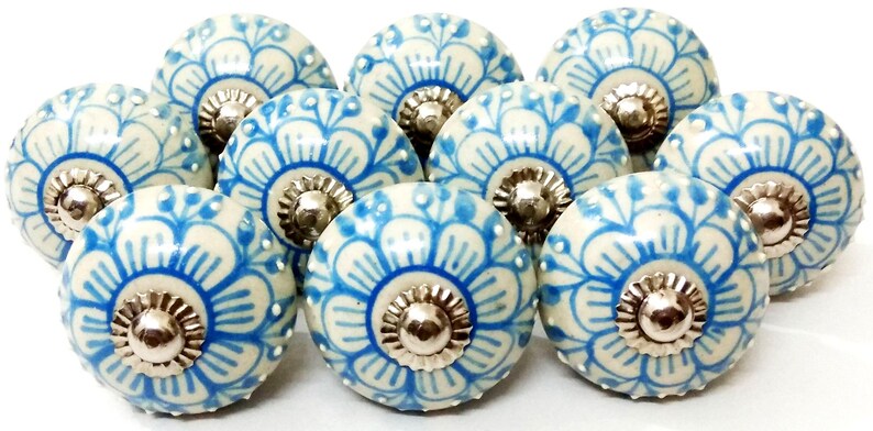 Peut inclure: Ensemble de boutons de meubles en c&eacute;ramique avec un motif floral bleu et cr&egrave;me. Chaque bouton a une base m&eacute;tallique argent&eacute;e. Les boutons sont ronds et d&eacute;coratifs, adapt&eacute;s &agrave; divers meubles. Le design est sym&eacute;trique.