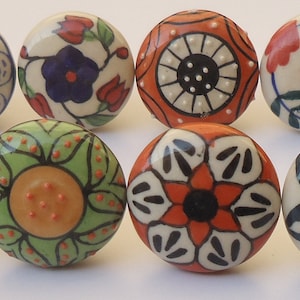 Pode incluir: Doze bot&otilde;es de gaveta de cer&acirc;mica com v&aacute;rios padr&otilde;es florais e geom&eacute;tricos em tons de branco, vermelho, laranja, verde, azul e preto.