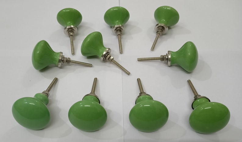 May include: Ten green ceramic cabinet knobs with silver metal screws. The knobs have a rounded, slightly oval shape.
