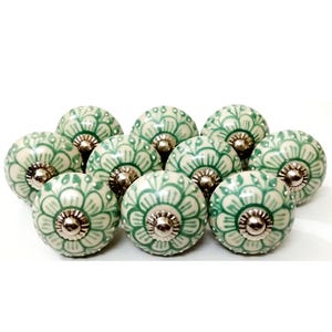 Peut inclure: Dix boutons de meuble en c&eacute;ramique, cr&egrave;me et vert. Chaque bouton pr&eacute;sente un motif floral vert sur un fond cr&egrave;me. Les boutons ont des fixations m&eacute;talliques argent&eacute;es.