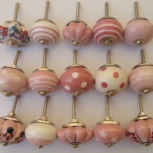 以下が含まれることがあります： 様々なパターン、ドット、ストライプ、花柄など、ピンクと白のセラミック製のキャビネットノブ15個セット。各ノブにはシルバーの金属ステムが付いています。