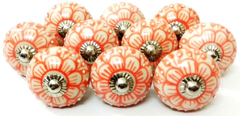 Peut inclure: Ensemble de dix boutons de meubles en c&eacute;ramique. Chaque bouton pr&eacute;sente une base cr&egrave;me avec un motif floral corail. Les boutons ont une base en m&eacute;tal argent&eacute;. Id&eacute;al pour ajouter une touche d&eacute;corative aux meubles.