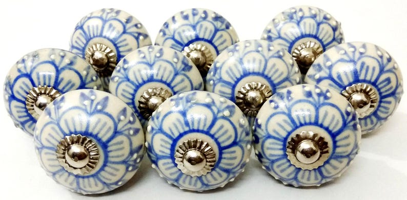 Peut inclure: Ensemble de dix boutons de meubles en c&eacute;ramique. Chaque bouton est rond, avec une base cr&egrave;me et un motif floral bleu. Les boutons ont une base et une vis en m&eacute;tal argent&eacute;. Ces boutons d&eacute;coratifs sont parfaits pour ajouter une touche d'&eacute;l&eacute;gance aux meubles.