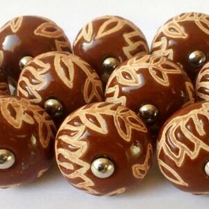 Peut inclure: Dix boutons de meuble en c&eacute;ramique marron avec un motif de feuilles cr&egrave;me. Chaque bouton a une finition brillante et une vis en m&eacute;tal argent&eacute;. Ces boutons d&eacute;coratifs sont parfaits pour les meubles.
