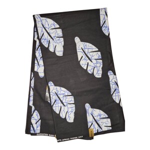 May include: Black fabric with a white leaf pattern and blue vein-like details. The fabric is folded and appears to be a textile, possibly for clothing or home decor. The text "GUARANTEED BLOCK" is visible.
