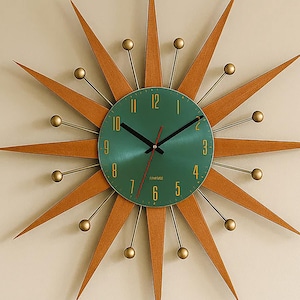 May include: A mid-century modern starburst clock with a teal face and wooden rays. The clock has gold-coloured accents and black hands. The clock is mounted on a cream-coloured wall.