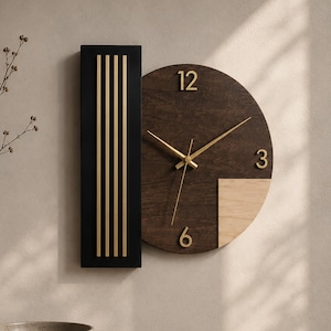 May include: A wall clock featuring a circular dark wood face with gold-coloured numerals 12, 3, and 6, and gold-coloured hands. A vertical black rectangular panel with four gold-coloured vertical lines is attached to the left side of the clock face.