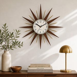 May include: A mid-century modern starburst clock with a brown wooden frame and gold accents. The clock face is white with black numerals. The clock is mounted on a white wall above a wooden console table with decorative items.