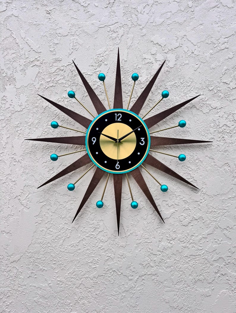 May include: A mid-century modern style wall clock with a black face, gold hands, and turquoise accents. The clock has a starburst design with 12 points.