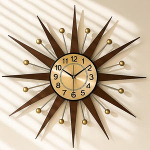 May include: A starburst wall clock with a gold-tone face and black numerals. The clock has brown wooden rays extending outward, with gold-colored spheres at the tips. The clock hands are black. A decorative piece for any room.