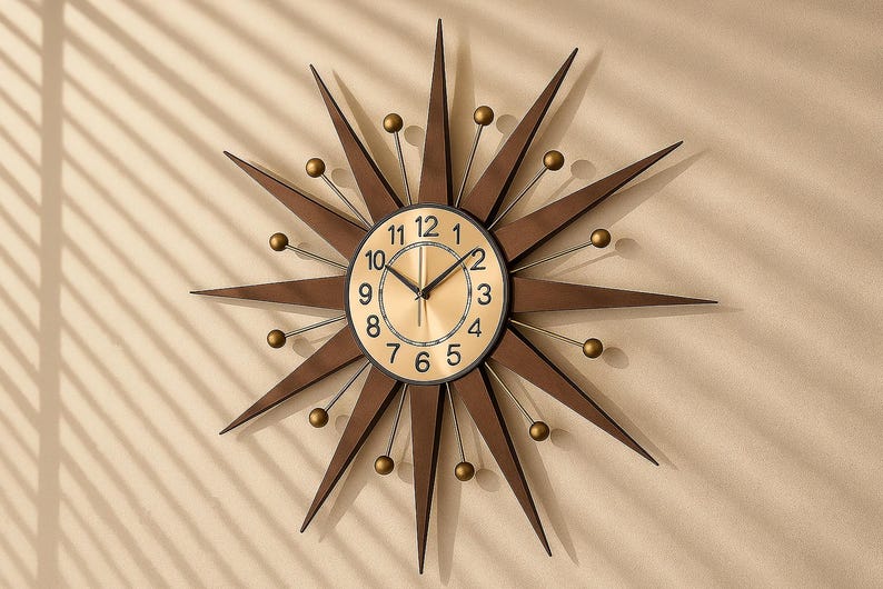 May include: A starburst wall clock with a gold-tone face and black numerals. The clock has brown, pointed rays extending outward, with small gold-colored spheres at the tips. The clock is mounted on a beige wall.