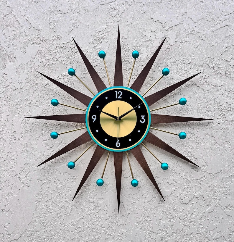 May include: A brown and gold starburst clock with turquoise accents. The clock face is black with gold numbers and hands.