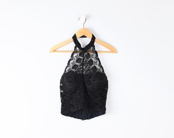 Può includere: Top nero con scollo halter in pizzo, con un corpetto aderente e un'overlay trasparente. Il top è appeso a un appendiabiti in legno su uno sfondo bianco.