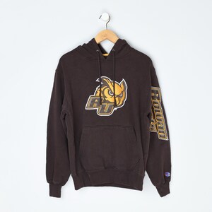 May include: A brown Champion hoodie with a large owl logo and "RU" in gold and white. The left sleeve features the word "Rowan" in gold. The hoodie has a front pocket and a drawstring hood.