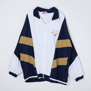 May include: A white, blue, and gold windbreaker jacket with a zipper closure. The jacket has a large "JUST DO IT" logo on the front with a Nike swoosh.