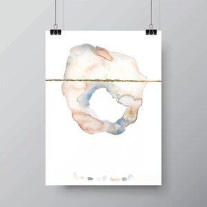 May include: Abstract watercolor art print featuring a soft, organic shape in muted tones of peach, gray, and blue, bisected by a thin, gold horizontal line. The artwork is displayed on white paper, held by black binder clips.