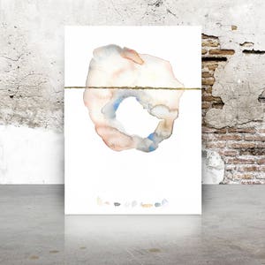May include: Watercolor abstract art print featuring a central organic shape in muted tones of peach, blue, and gray, bisected by a thin gold line. The artwork is displayed on a white background, with a collection of small, colorful shapes at the bottom.