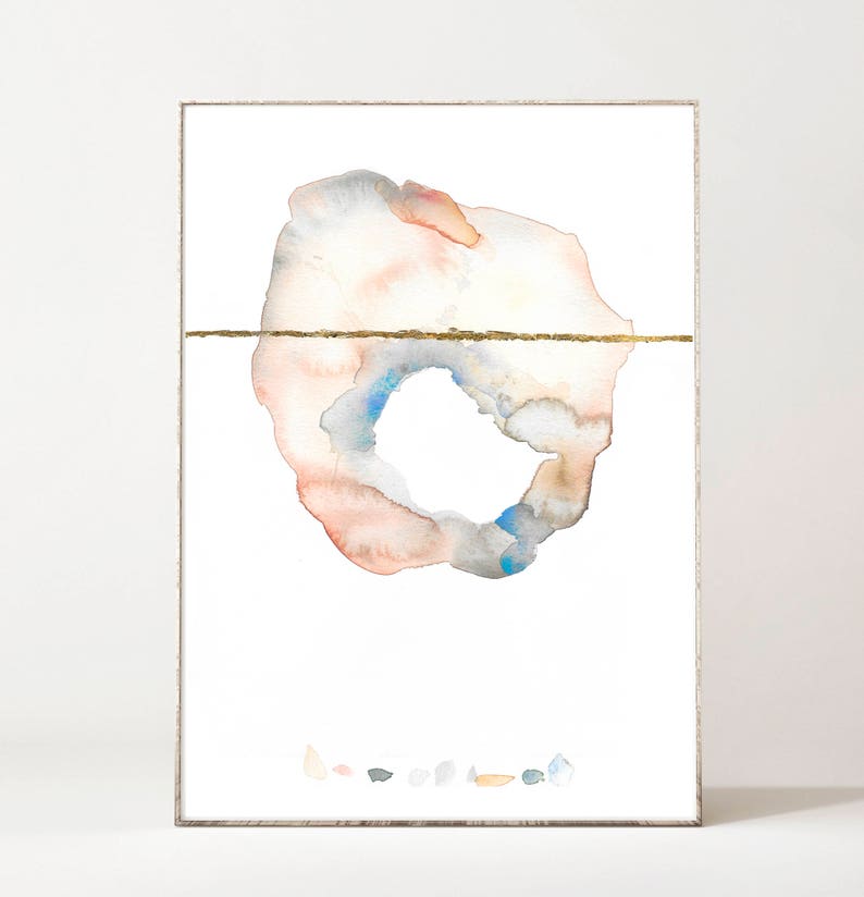 May include: Abstract watercolor art print in a silver frame. The artwork features a circular design with peach, blue, and gray hues, bisected by a gold line. Small, colorful shapes are at the bottom.