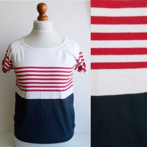 K&ouml;nnte beinhalten: Ein wei&szlig;- und marineblaues, kurz&auml;rmeliges Shirt mit roten Streifen. Das Shirt hat einen runden Ausschnitt und eine lockere Passform.