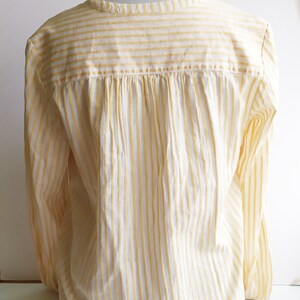 May include: A white and yellow striped long-sleeve shirt with a gathered back.