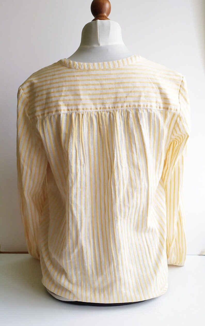 May include: A white and yellow striped long-sleeve shirt with a gathered back.
