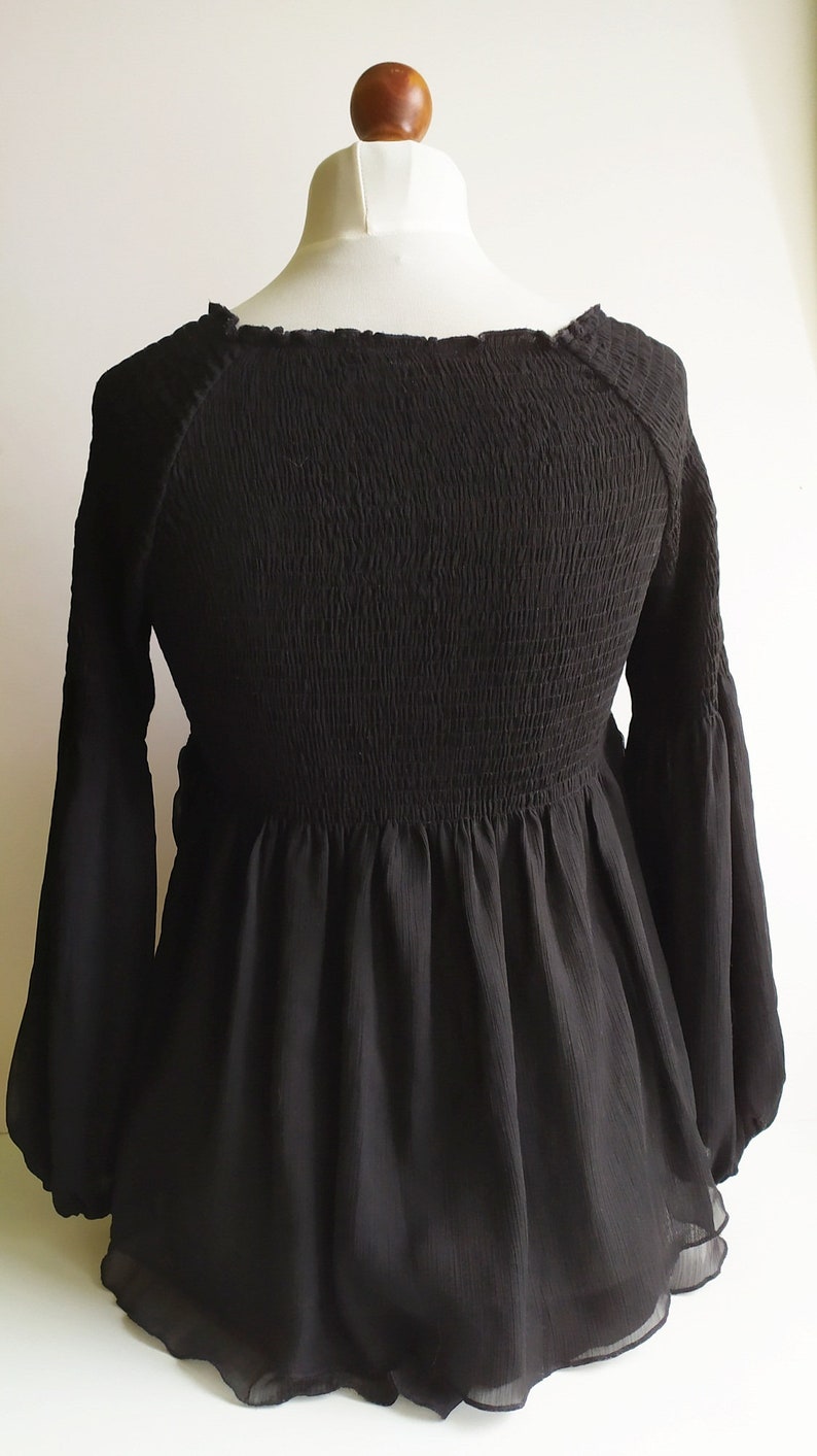 May include: A black, long-sleeved blouse with a smocked bodice and a ruffled hem.