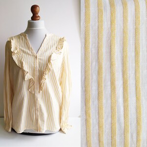 May include: A yellow and white striped long-sleeved blouse with a ruffled neckline.