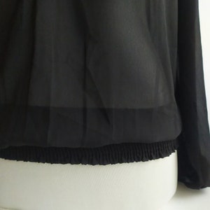 May include: Black sheer blouse with long sleeves and an elastic waistband.