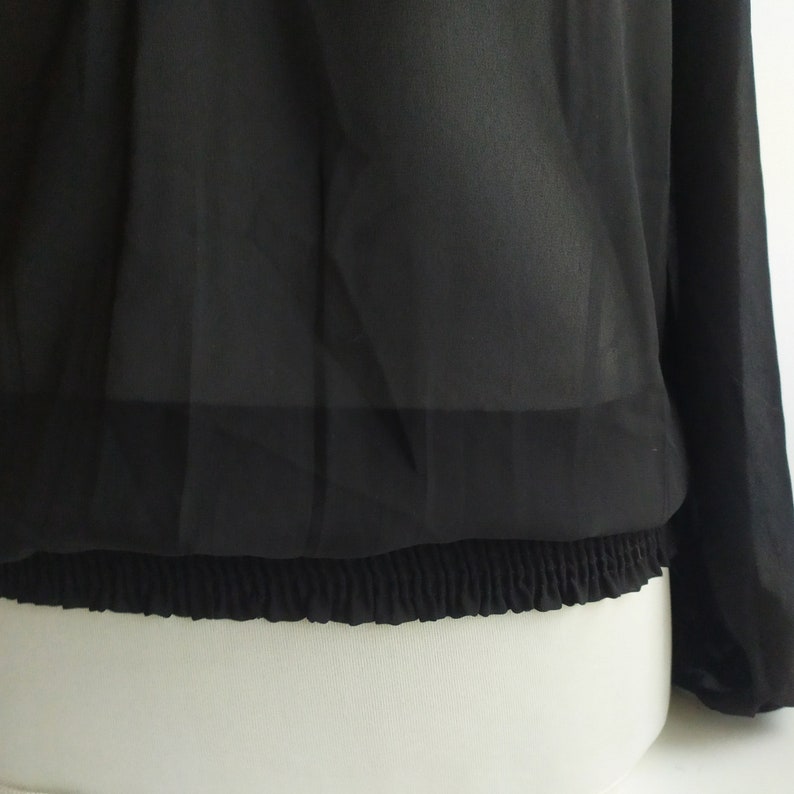 May include: Black sheer blouse with long sleeves and an elastic waistband.