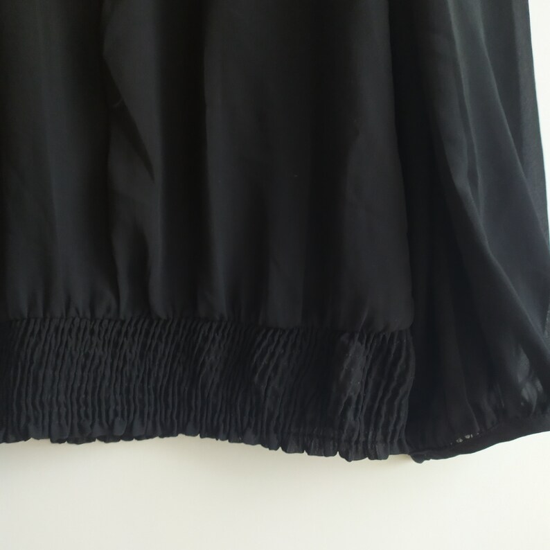 May include: Black sheer top with a gathered elastic band at the bottom.