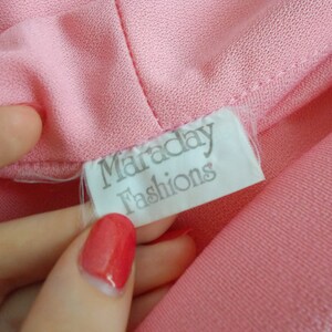 May include: A white tag with the text "Maraday Fashions" on a pink fabric background.
