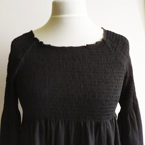 May include: A black smocked dress with long sleeves and a round neckline.
