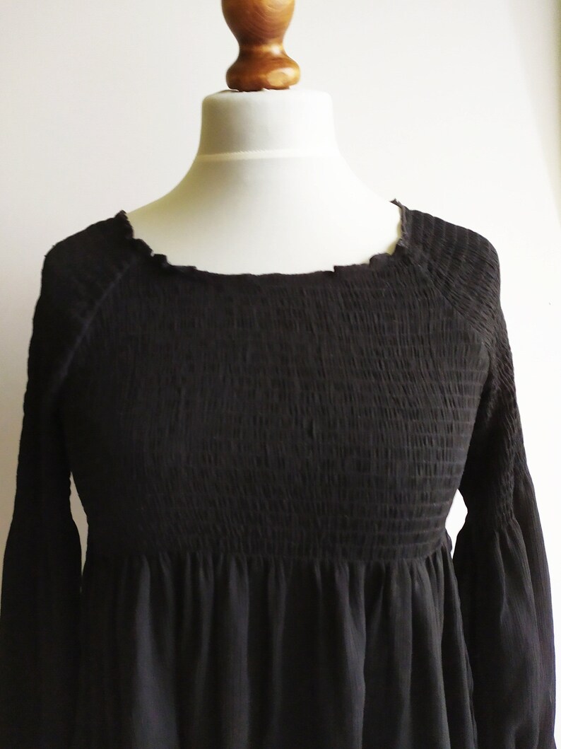 May include: A black smocked dress with long sleeves and a round neckline.