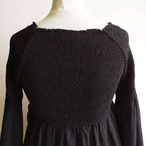 May include: A black, long-sleeved, smocked top with a square neckline and a gathered skirt.