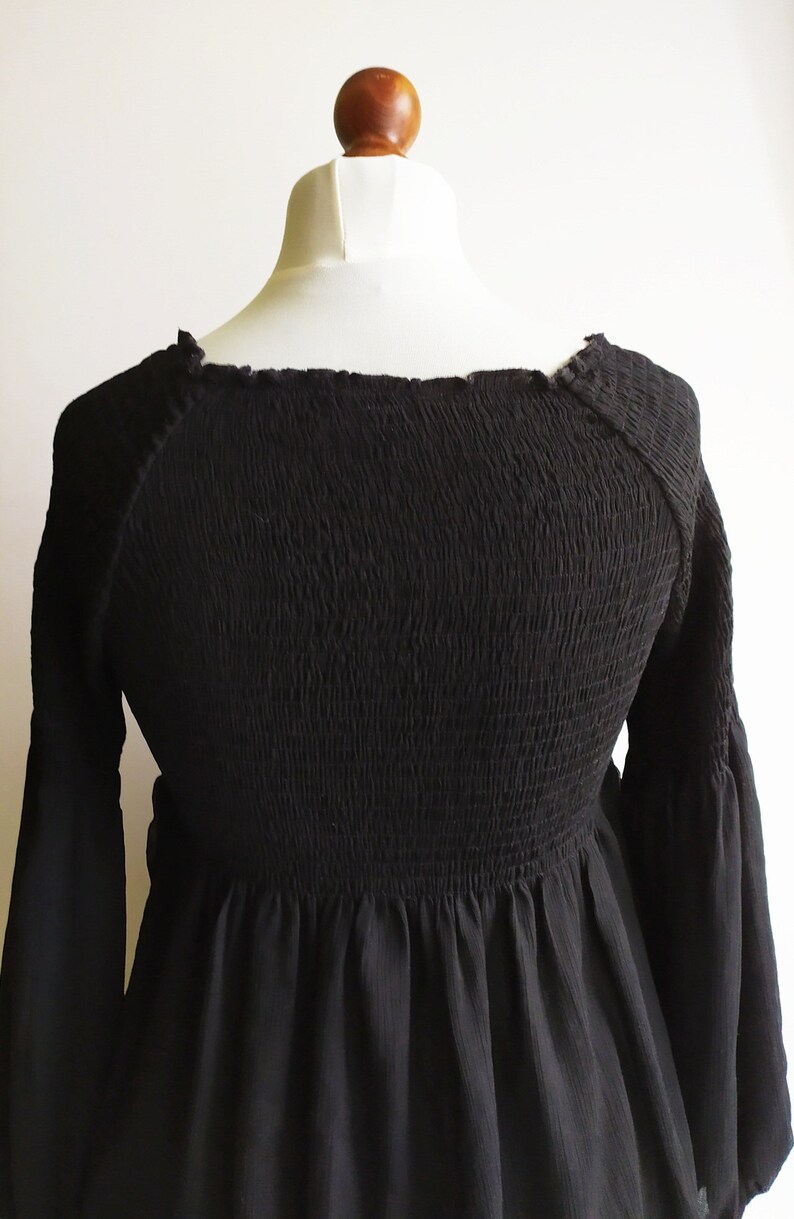 May include: A black, long-sleeved, smocked top with a square neckline and a gathered skirt.